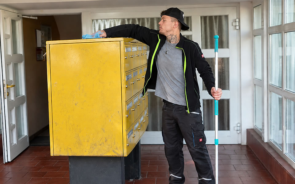 Man reinigt im Treppenhaus den Briefkasten